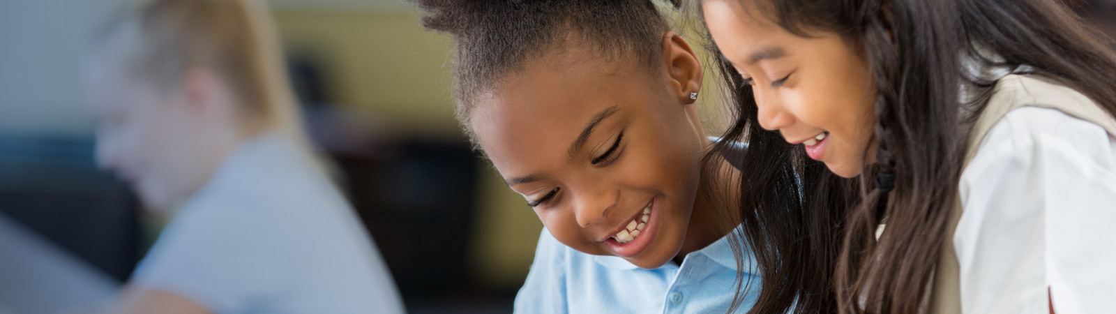 An African-American and Asian-American girl work on schoolwork together